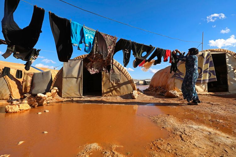 A woman hangs laundry in a flooded refugee camp in Idlib province, Syria, on December 21, 2021.