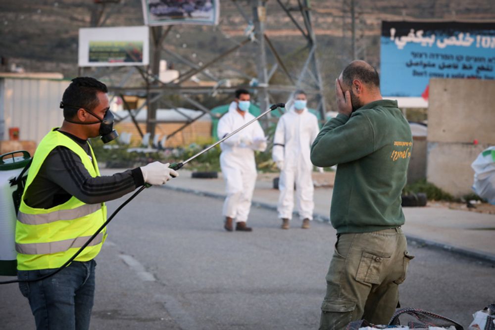 عملية تعقيم العمال الفلسطينيين الذين عادوا من العمل في إسرائيل من أجل وقف انتشار فيروس كورونا، مدخل قرية حوسان بالضفة الغربية، 29 مارس، 2020.