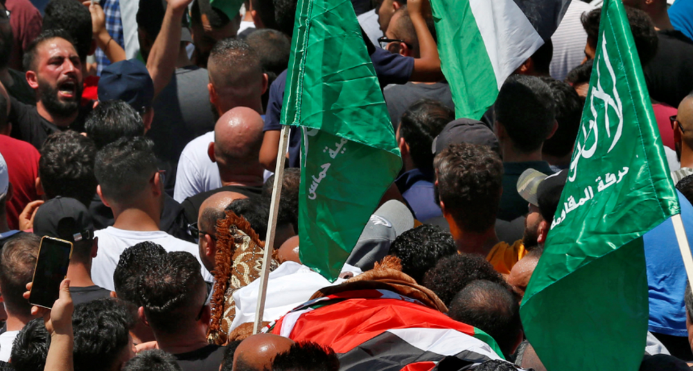 Des personnes en deuil marchent dans un cortège funéraire avec le corps du militant et critique de l'Autorité palestinienne Nizar Banat, le 25 juin 2021