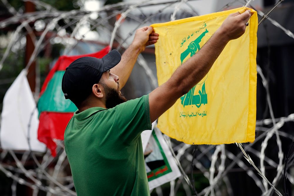 أحد مؤيدي حزب الله يهتف شعارات وهو يحمل علم حزبه خلال احتجاج بالقرب من السفارة الأمريكية شمال شرق بيروت ، لبنان ، في 10 يوليو / تموز 2020.