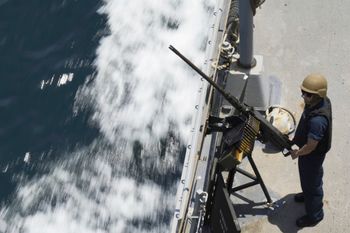 A U.S. Navy sailor stands guard next to a machine gun aboard the USS Paul Hamilton in the Strait of Hormuz.