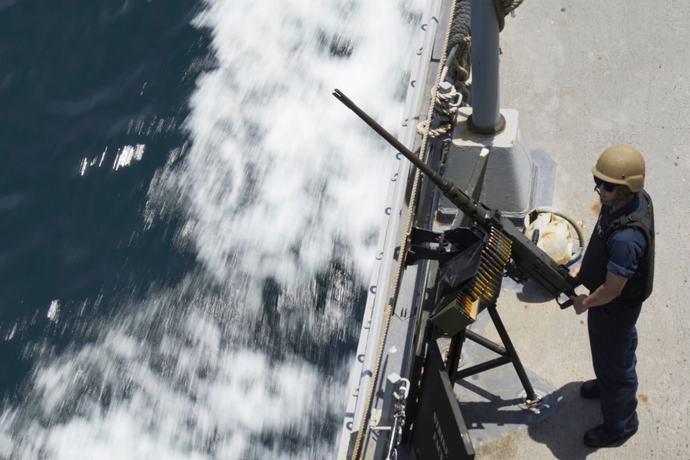 A US Navy sailor stands guard next to a machine gun aboard the USS Paul Hamilton in the Strait of Hormuz.