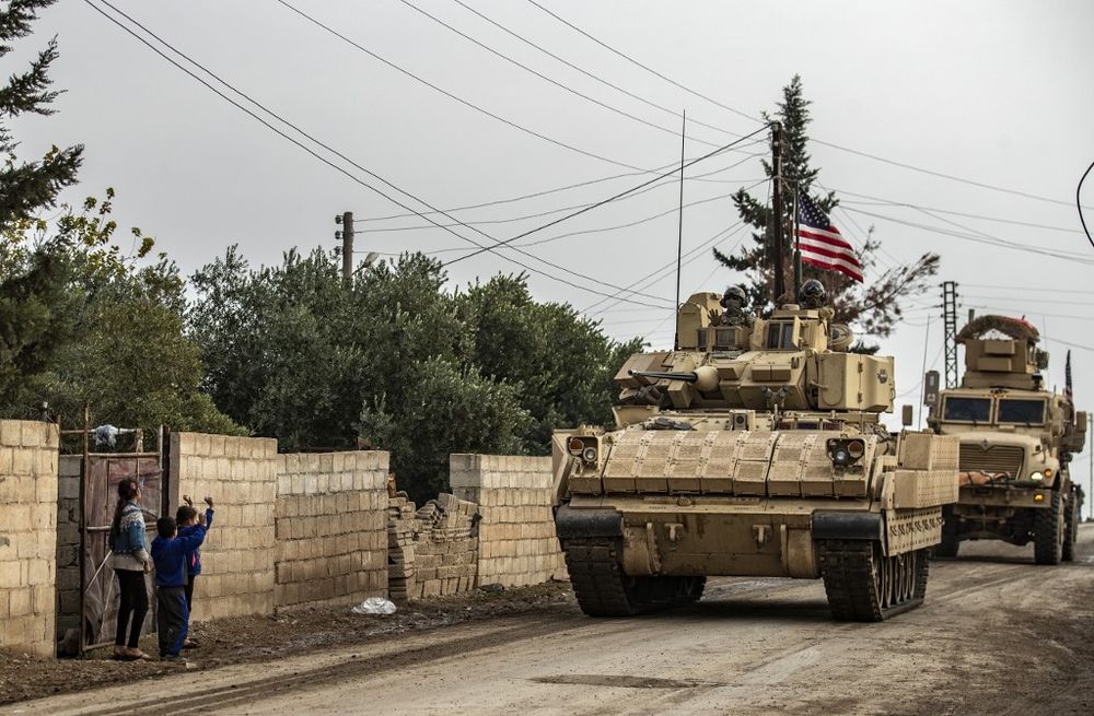 Children gesture as US troops patrol in their military vehicles on the roads of the Syrian town of al-Jawadiyah and meet the inhabitants, in the northeastern Hasakeh province, near the border with Turkey, on December 17, 2020.