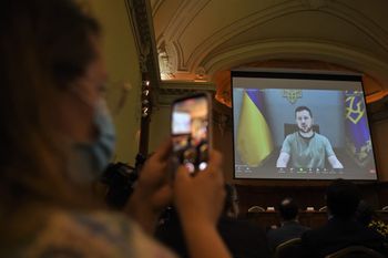 A woman records Ukraine's President Volodymyr Zelensky speaking during a videoconference held at the Universidad Catolica in Santiago, Cile on August 17, 2022.