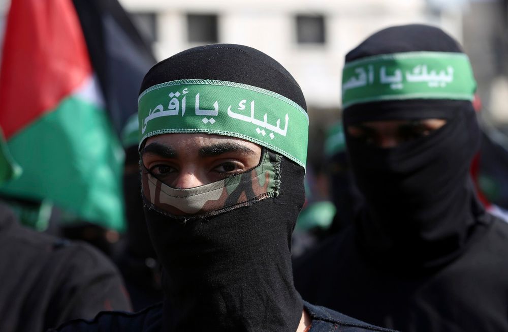 Masked Hamas militants wave their national flags during a protest against the Mideast plan announced by U.S. President Donald Trump in Gaza City, Friday, Feb. 21, 2020