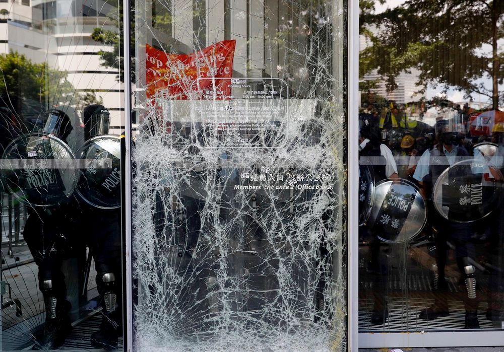 Police officers stand guard behind the cracked glass wall of the Legislative Council after protesters try to break into in Hong Kong on Monday, July 1, 2019