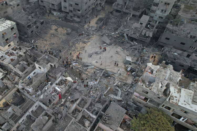 Palestinians walk about buildings destroyed in the Israeli bombardment in the Nusseirat refugee camp in the Gaza Strip on Sunday, Oct. 29, 2023