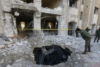 A member of the Syrian security forces checks a crater caused by a reported Israeli missile strike in Damascus, Syria.