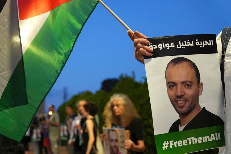 Protesters gather with a Palestinian flag outside the hospital where Khalil Awawdeh, pictured in the placards, a prisoner on hunger strike, is being treated, in Be'er Yaakov, Israel, on August 13, 2022.