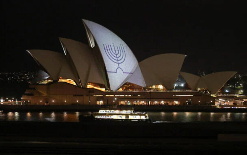 Une menorah de Hanouka est projetée sur les voiles de l'Opéra de Sydney en mémoire des victimes d'une fusillade à Bondi Beach, à Sydney, le 15 décembre 2025.