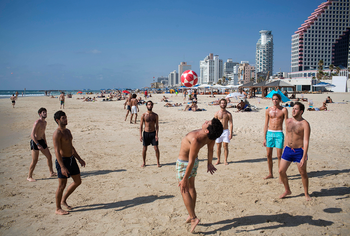Israelis play with a ball at the Mediterranean Sea beach front, which is normally crowded at this time of year, in Tel Aviv, Israel, Wednesday, July 9, 2014.