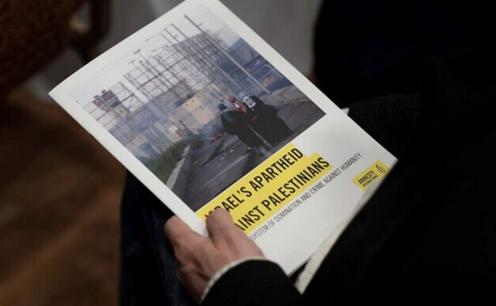 Un journaliste tient un exemplaire du rapport d'Amnesty International intitulé "L'apartheid d'Israël contre les Palestiniens", à Jérusalem, le 1er février 2022.