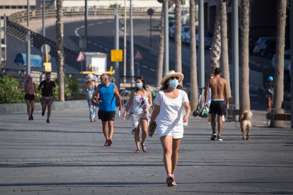 Israelis walk near the beach in Tel Aviv wearing face masks during the coronavirus pandemic, on October 15, 2020.