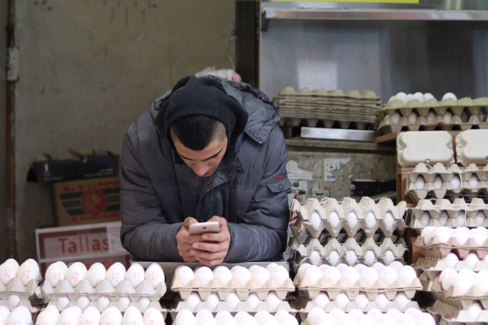 A salesman on his phone while selling eggs at an eggstand in the Machane Yehuda Market, Jerusalem, January 27, 2018.