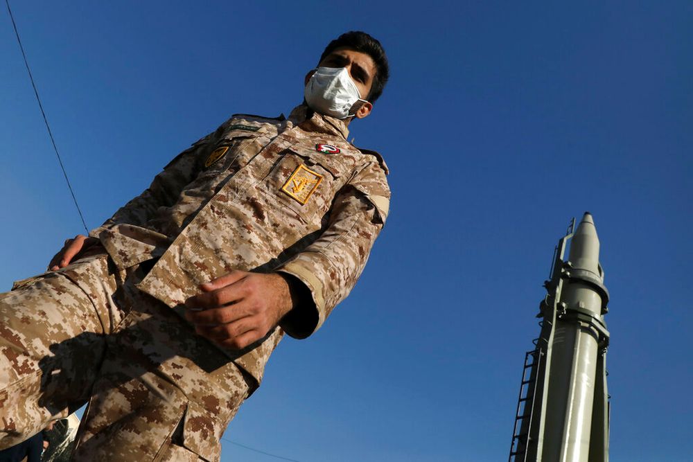 A member of Iran's Islamic Revolutionary Guard Corps walks past a Qiam missile in Tehran, Iran, on January 7, 2022.
