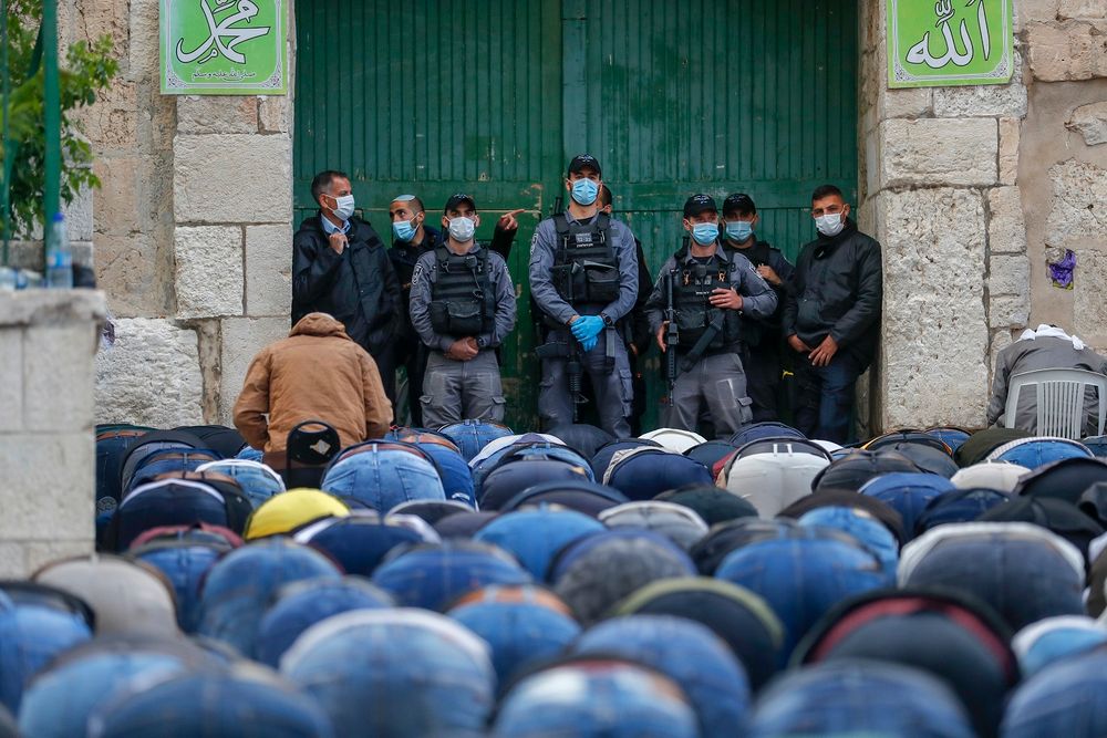 Israeli security forces clad in masks due to the coronavirus pandemic look on as Muslim worshipers gather to attend the prayers of Eid al-Fitr outside the closed Aqsa mosque complex in Jerusalem's old city, on May 24, 2020