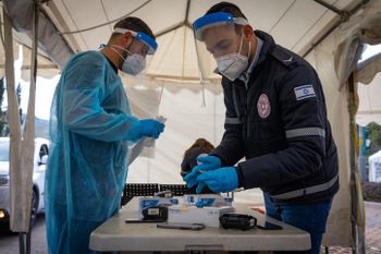 Israeli healthcare workers collecting Covid test samples at a drive through testing facility in Jerusalem, on March 22, 2022.