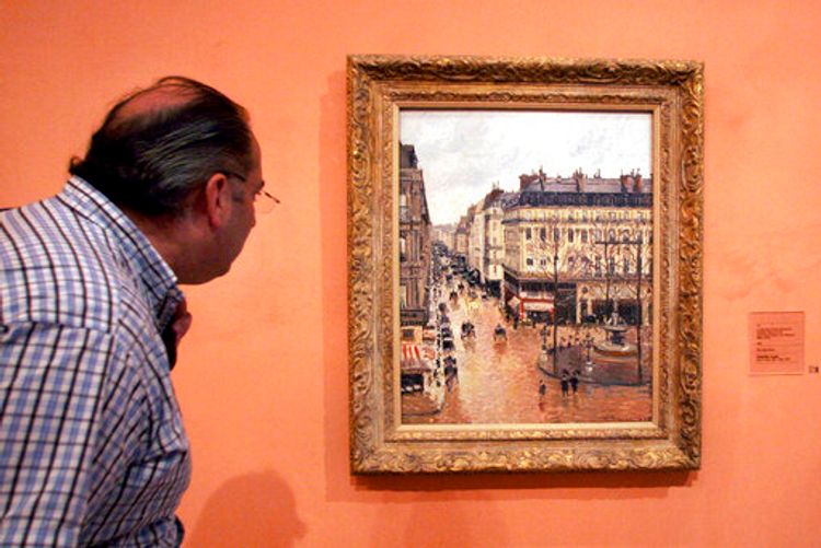 A visitor viewing the impressionist painting called "Rue St.-Honore, Afternoon, Effect of Rain" painted in 1897 by Camille Pissarro, on display in the Thyssen-Bornemisza Museum in Madrid, Spain, May 12, 2005.