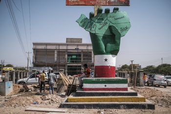 People stand next to the “Independence Monument” depicting a hand holding a map of the country, in the city of Hargeisa, Somaliland, on September 19, 2021.