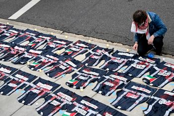 A demonstrator lays candles on the ground next to press vest covered in red paint during a pro-Palestinian protestat the White House Correspondents' Association Dinner, April 27, 2024, in Washington.