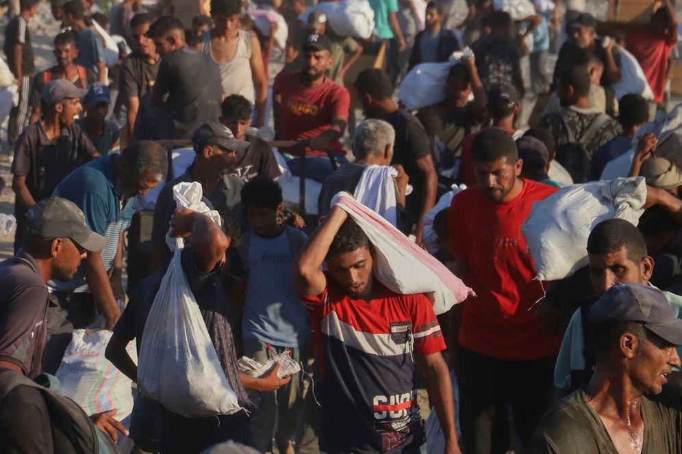 Palestinians carry packages of food taken from a humanitarian aid convoy that moved along the Morag corridor near Rafah, in the southern Gaza Strip