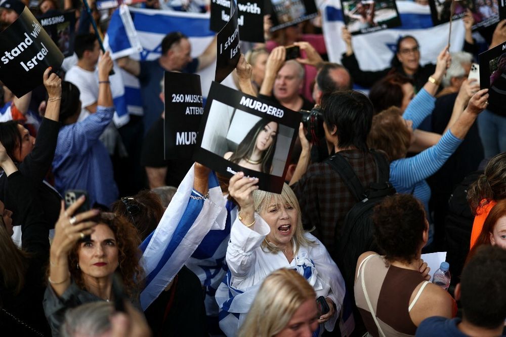 Посетитель держит изображение немецко-израильской женщины Шани Лук, которая принимает участие в «Бдении за Израиль» напротив входа на Даунинг-стрит, официальную резиденцию премьер-министра Великобритании, в Лондоне, 9 октября 2023 года.