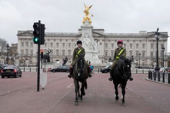 جنديان من الفرسان يمتطيان خيولهما أثناء مرورهما بقصر باكنغهام الأول، أحد أماكن الإقامة الرسمية للملك تشارلز الثالث، بينما يسير المشاة في لندن، الثلاثاء 6 فبراير 2024.