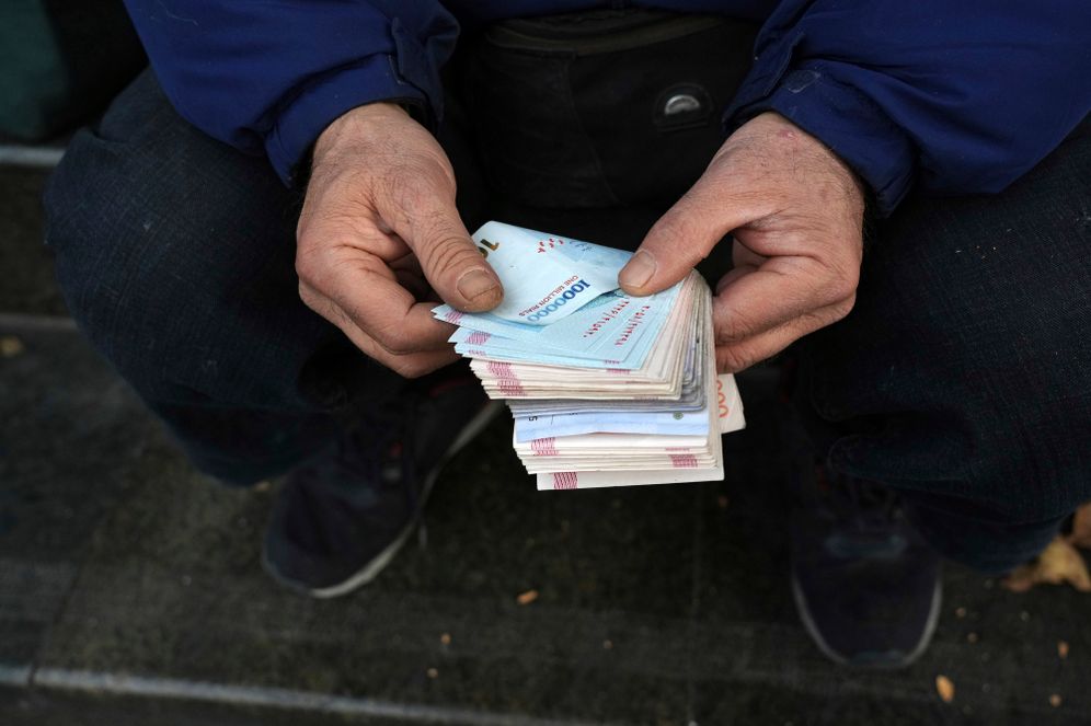 AP Photo/Vahid Salemi A street money exchanger poses for a photo without showing his face as he counts Iranian banknotes at a commercial district in downtown Tehran, Iran, Friday, Dec. 23, 2022.