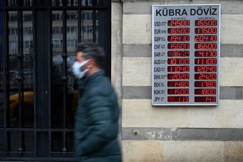 A man walks in front of a screen showing rates against Turkish lira near a currency exchange agency in Istanbul, Turkey, on December 16, 2021.