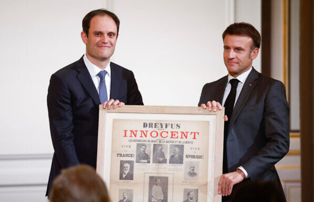 Le président du CRIF Yonathan Arfi, offre une affiche à Emmanuel Macron, lors d'une cérémonie célébrant le 80e anniversaire du Conseil des institutions juives de France (CRIF) au palais de l'Élysée à Paris, le 18 mars 2024.