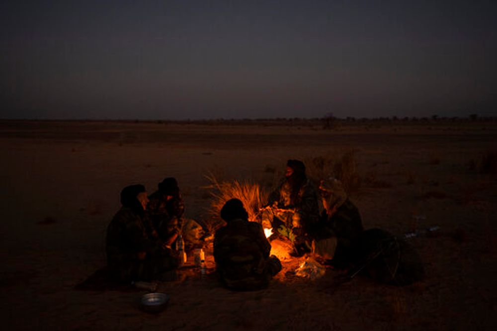 Polisario Front soldiers warm themselves by a fire near Bir Lahlou, Western Sahara, October 15, 2021.