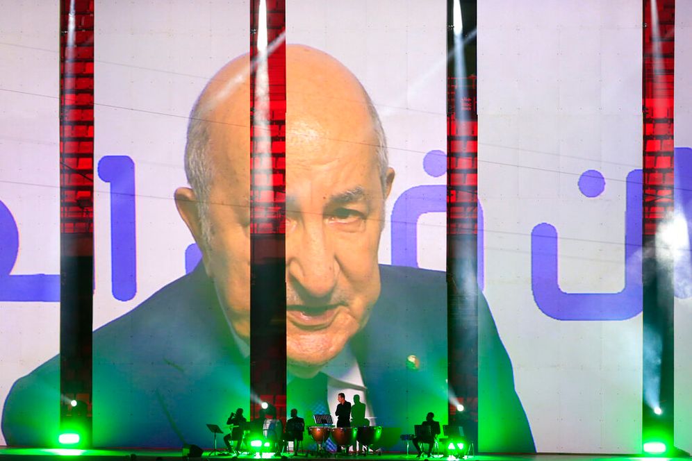 صورة للرئيس الجزائري عبد المجيد تبون في الخلفية بينما تعزف فرقة موسيقية خلال افتتاح دورة الألعاب المتوسطية في وهران ، الجزائر ، السبت 25 يونيو 2022.