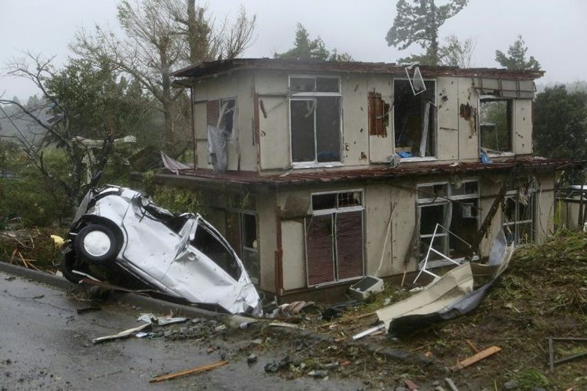 A vehicle lies in a ditch next to a badly damaged house in Chiba prefecture, east of Tokyo, after strong winds brought by Typhoon Hagibis hit the area