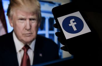 A phone screen displays a Facebook logo with the official portrait of former U.S. president Donald Trump on the background