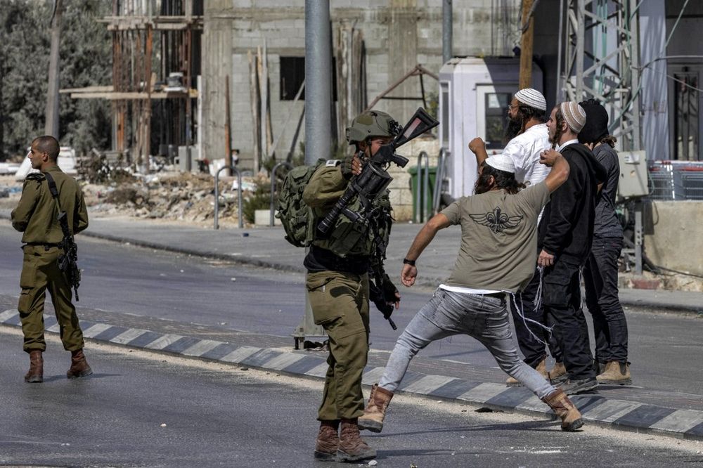 Israeli soldiers stand by as Israeli settlers throw stones at Palestinians during clashes in the town of Huwara in the West Bank on October 13, 2022.