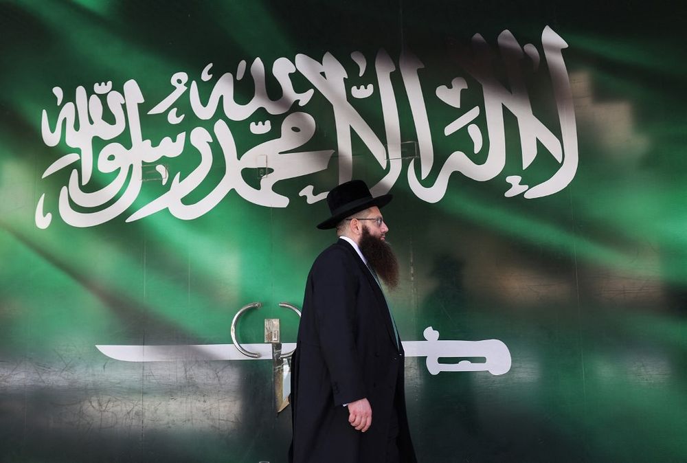 الحاخام الأمريكي الحسيدي يعقوب إسرائيل هرتسوغ يسير أمام بوابة مرسومة بالعلم السعودي، في العاصمة السعودية الرياض.