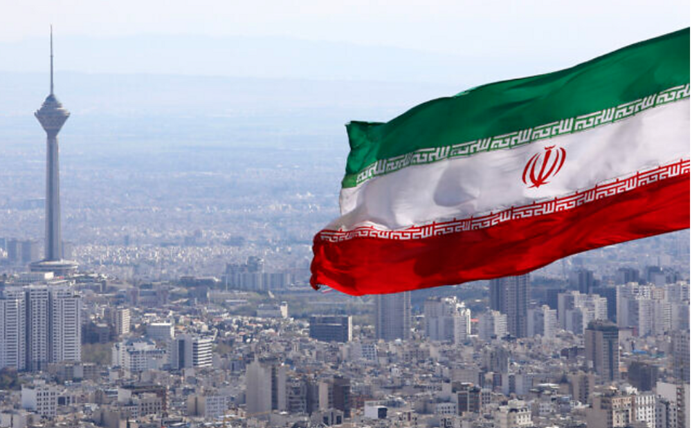 Sur cette photo d'archive du 31 mars 2020, le drapeau national iranien flotte alors que la tour de télécommunications Milad et d'autres bâtiments sont visibles à Téhéran, en Iran.