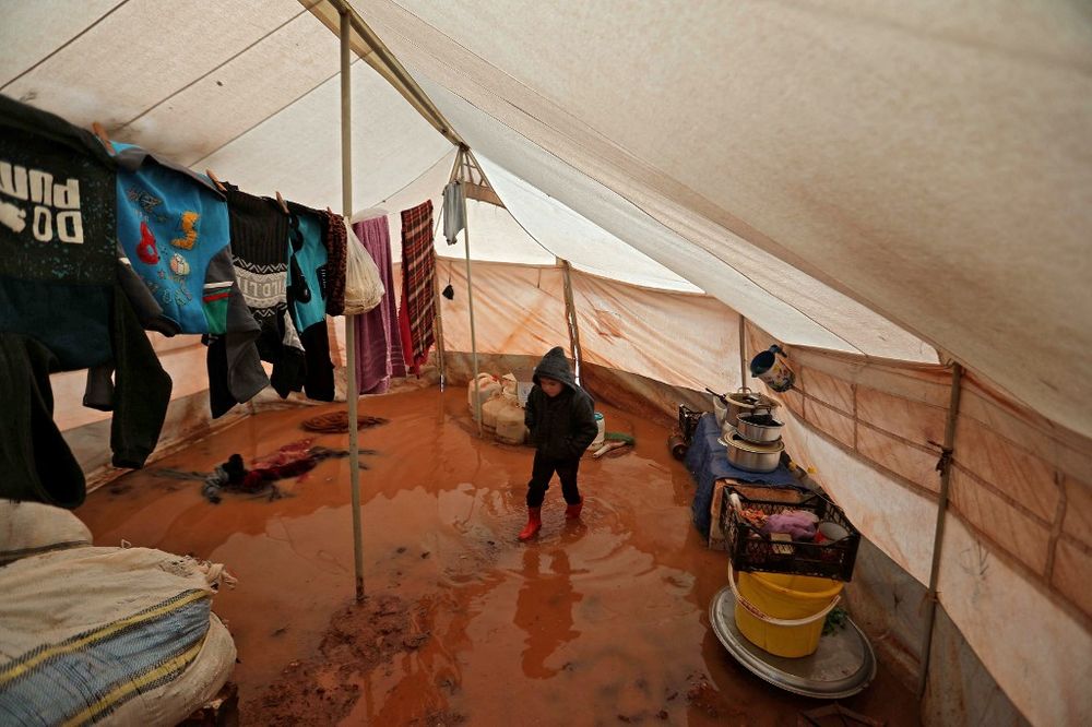 A child walks inside a flooded tent at a camp for the displaced by the village of Killi, near Bab al-Hawa by the border with Turkey, in Syria's northwestern Idlib province on December 20, 2021.