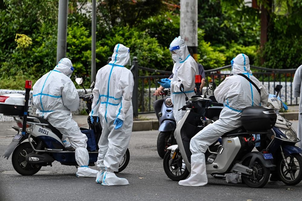 Policemen and officers stand on a street next to a neighborhood during a Covid-19 coronavirus lockdown in the Jing'an district in Shanghai on May 7, 2022.