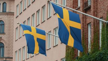 Still image of two Swedish flags waving on poles on the building on a windy day