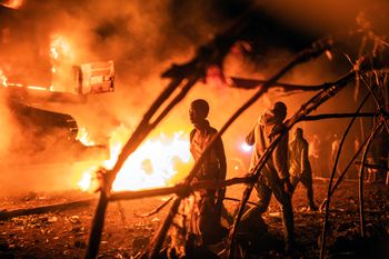 People walk by UN vehicles that were set on fire, in Goma, Democratic Republic of Congo.