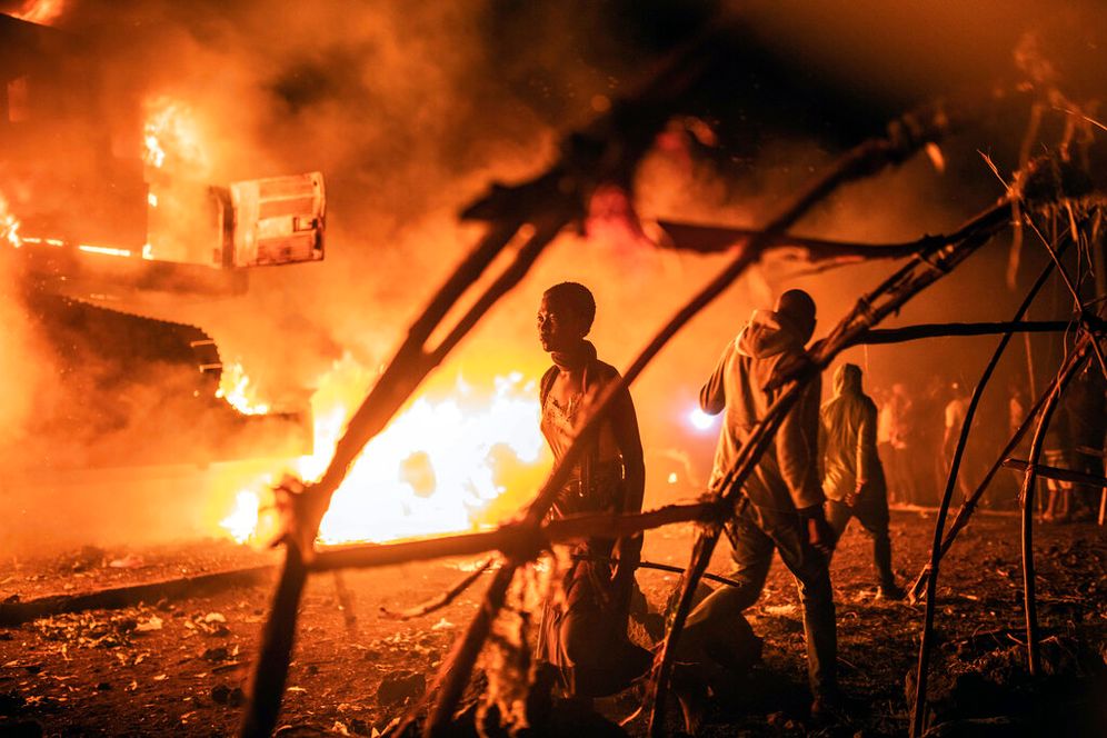 People walk by UN vehicles that were set on fire, in Goma, Democratic Republic of Congo.