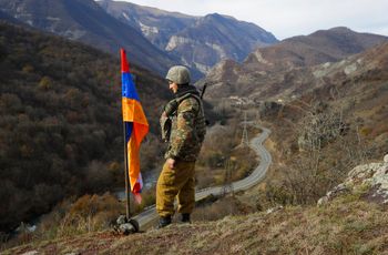 An ethnic Armenian soldier stands next to Nagorno-Karabakh's flag in the separatist region of Nagorno-Karabakh at a new border with Kalbajar district turned over to Azerbaijan, on November 25, 2020.