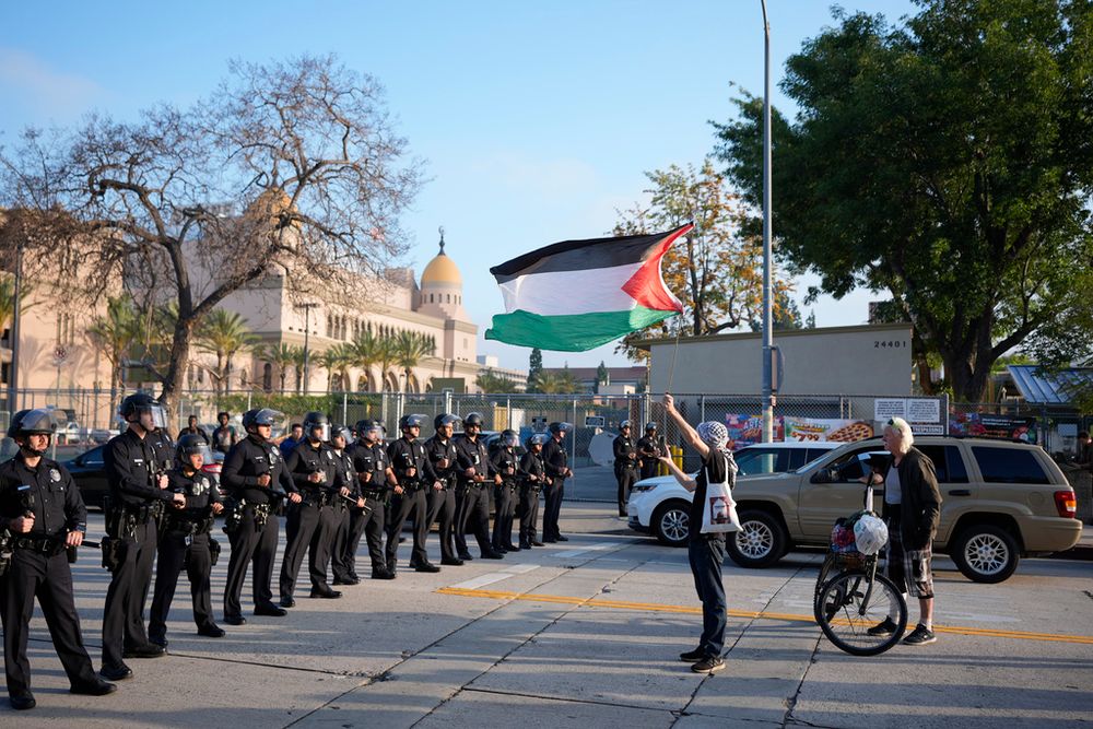 FILE - A pro-Palestinian demonstrator holds a flag in front of a police line after protesters were told to disperse at the Shrine Auditorium, where a commencement ceremony for graduates from Pomona College was being held, May 12, 2024, in Los Angeles.