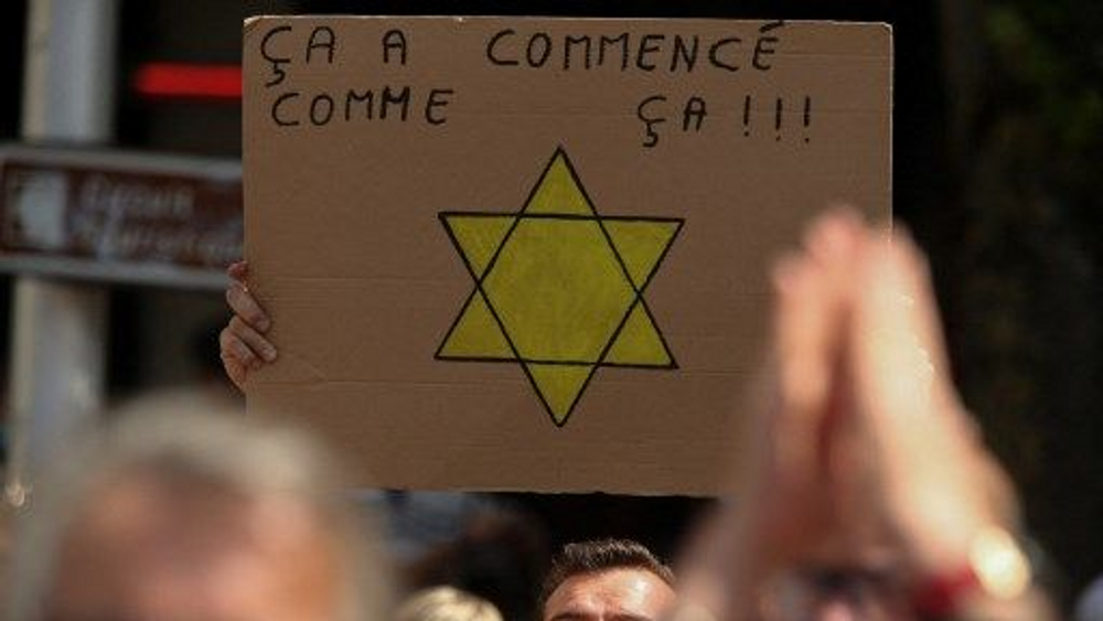 Un manifestant brandit une pancarte avec une étoile jaune portant la mention "ça a commencé comme ça" lors d'une manifestation anti-pass sanitaire à Reims le 31 juillet 2021