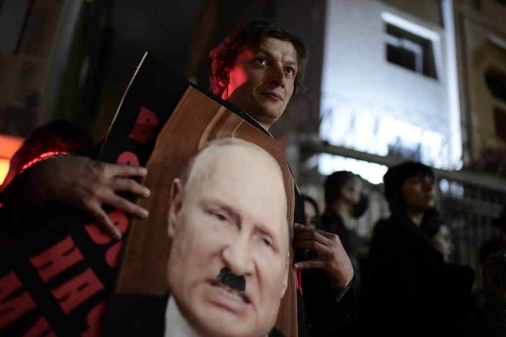 Protesters outside the Russian Embassy in Tel Aviv, Israel carry placards depicting Vladimir Putin as Nazi leader Hitler on February 24, 2022.
