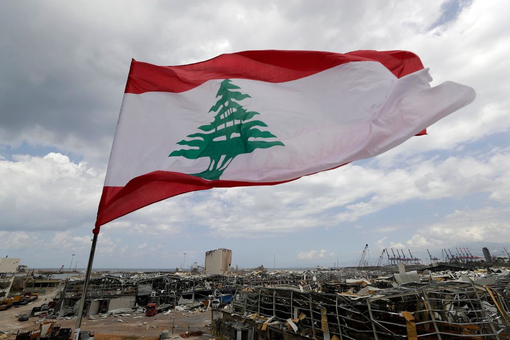 A Lebanese flag set by citizens flies in front the site of Tuesday's explosion that hit the seaport of Beirut, Lebanon, Sunday, Aug. 9, 2020