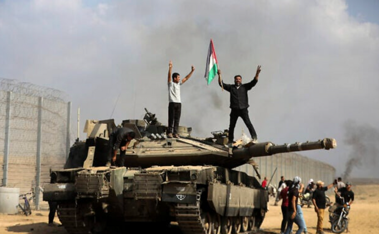 Des Palestiniens brandissent le drapeau national et célèbrent la destruction d'un char israélien à la clôture sud de la bande de Gaza, à l'est de Khan Younès, le 7 octobre 2023