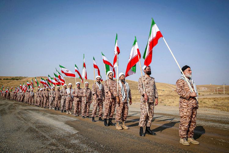 Clerics of the Islamic Revolutionary Guard Corps hold Iranian flags while attending a maneuver in northwestern Iran.