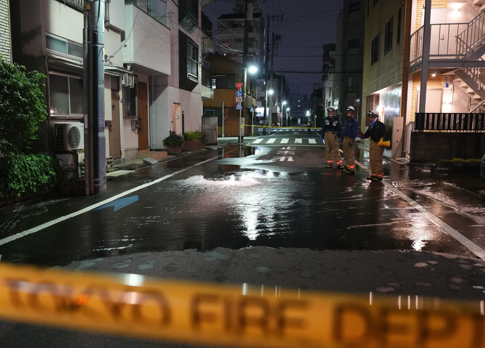 Les secours du Tokyo Fire Department se tiennent dans une rue partiellement inondée aux premières heures du dimanche 23 août 2026, après la rupture d’une canalisation d’eau provoquée par le séisme qui a frappé la région et les préfectures voisines.
